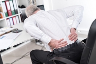 Mann im Büro mit Rückenschmerzen 