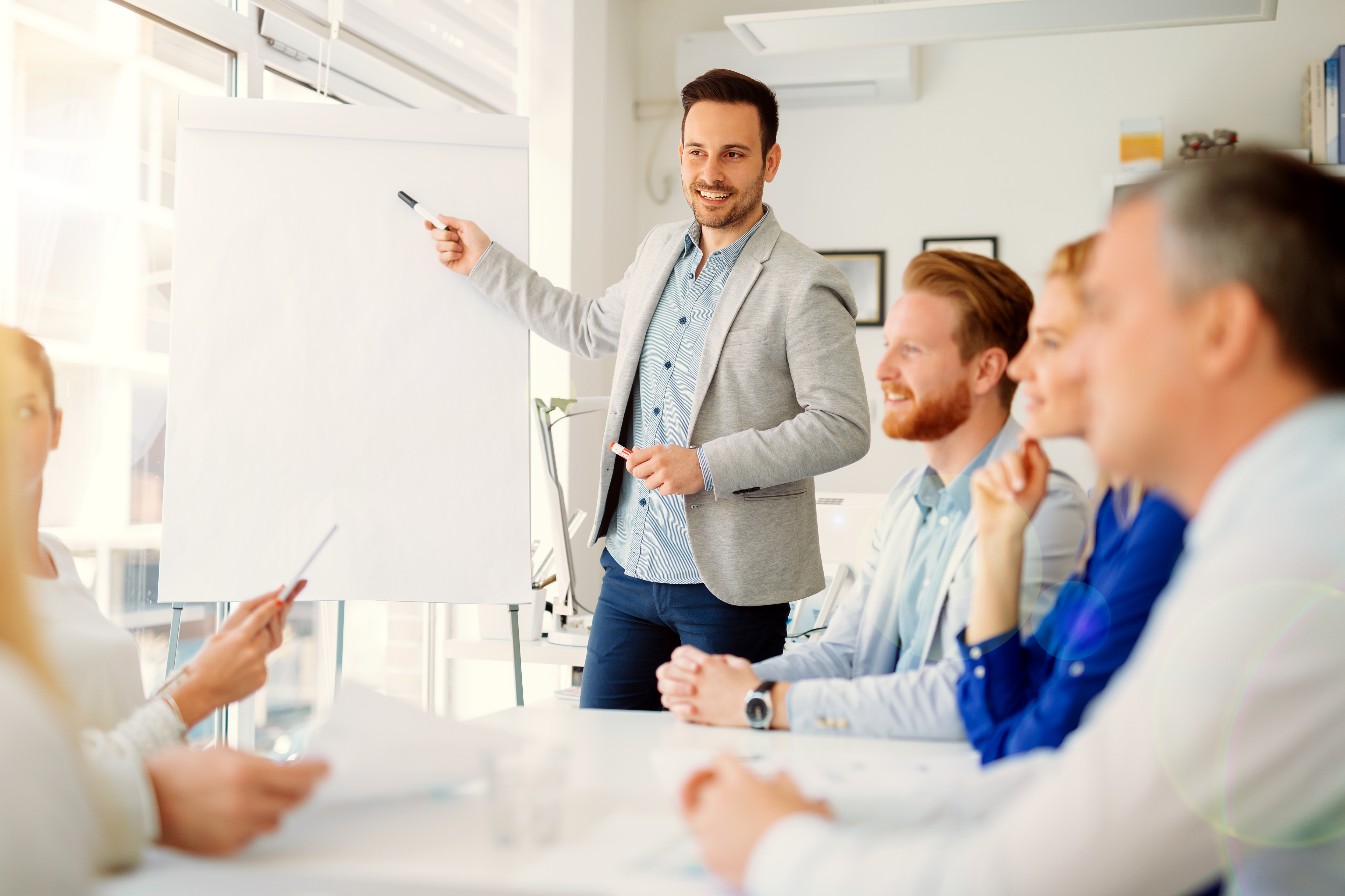 Mann neben Flipchart präsentiert vor Menschen